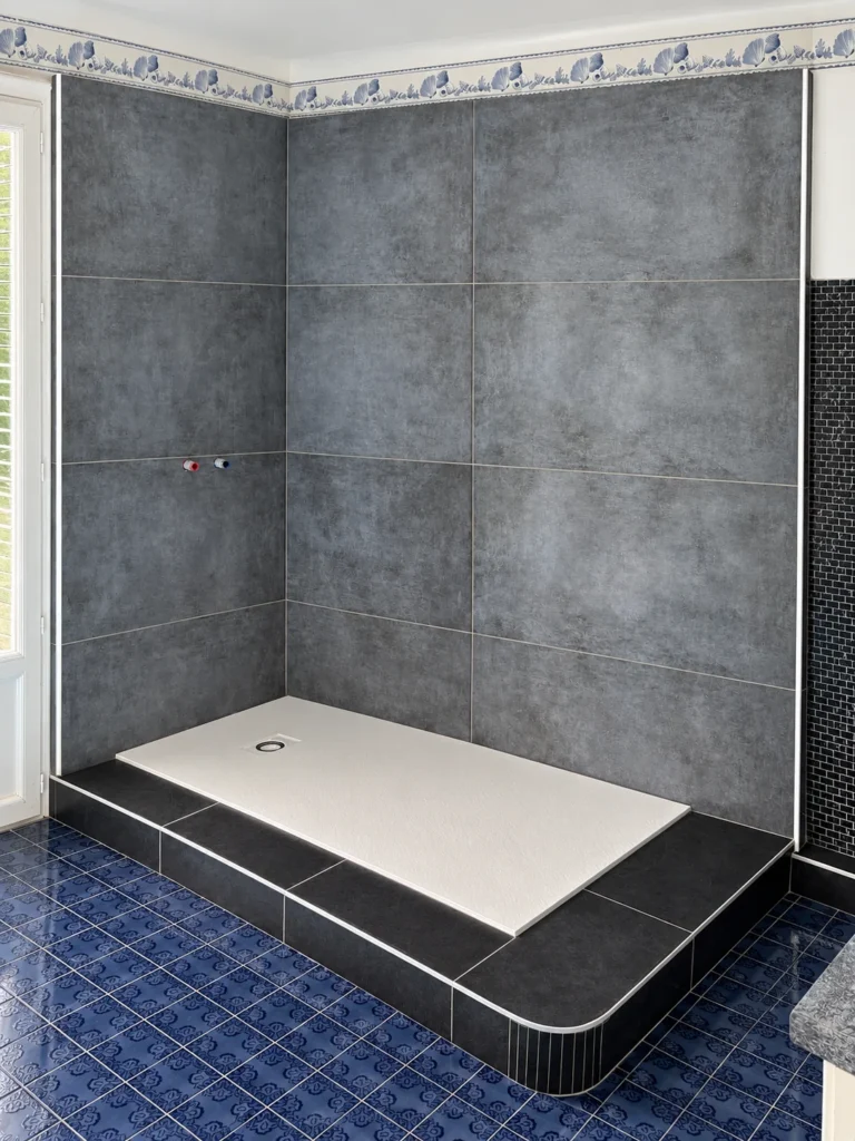 Douche en grands carreaux gris sur une estrade carrelée noire