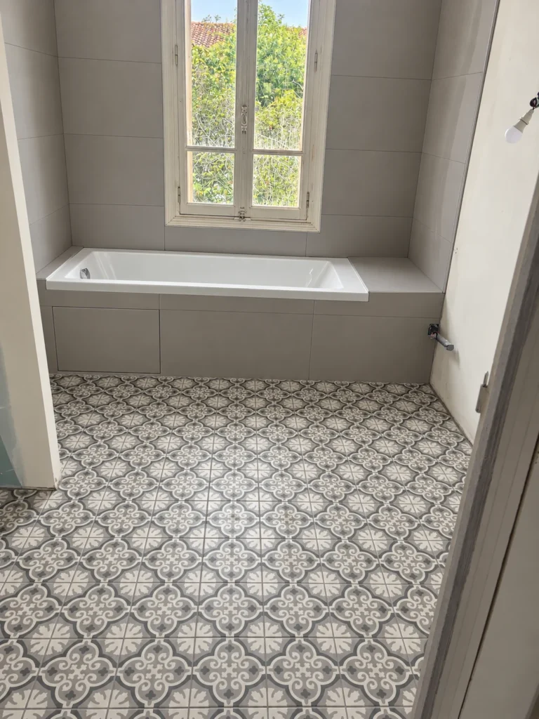 Sol décoratif à motifs devant une baignoire au tablier carrelé